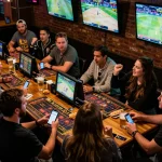 Red88 patrons engaged in sports betting action with mobile devices in a lively bar setting