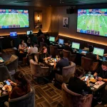 Patrons placing bets at TIP88 sports betting lounge with live game displays and a vibrant atmosphere.