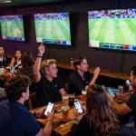 3BET sports enthusiasts placing bets at a lively venue with multiple screens.